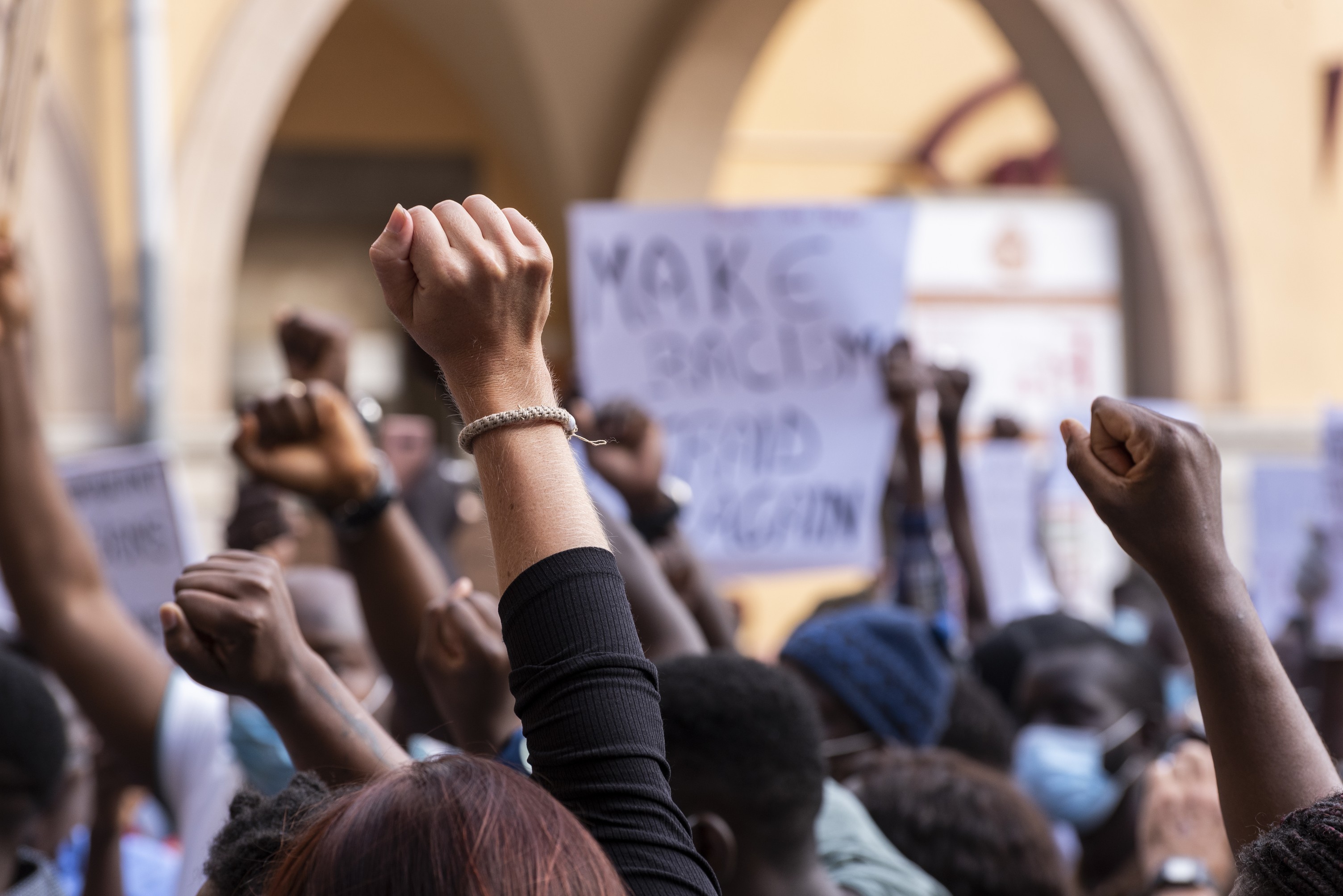 Wide shot of Anti-racism protesters raising their fists in solidarity