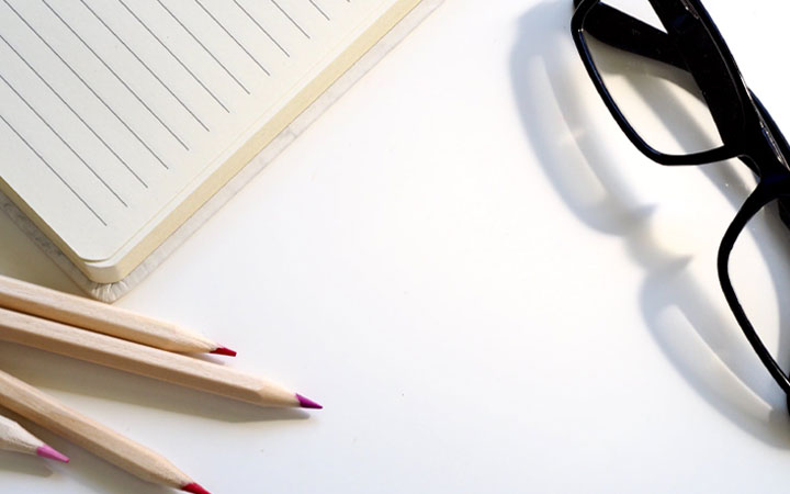 Desktop with notebook, pencil, and glasses