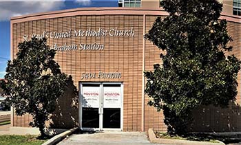 Photograph of the front of a light-brown brick building. The entrance is a set of double glass doors with signs saying "University of Houston College of Nursing Health Clinic" on each.