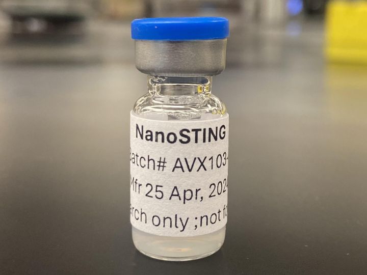 A small vial labeled “NanoSTING” with a blue cap. The vial is on a laboratory surface.