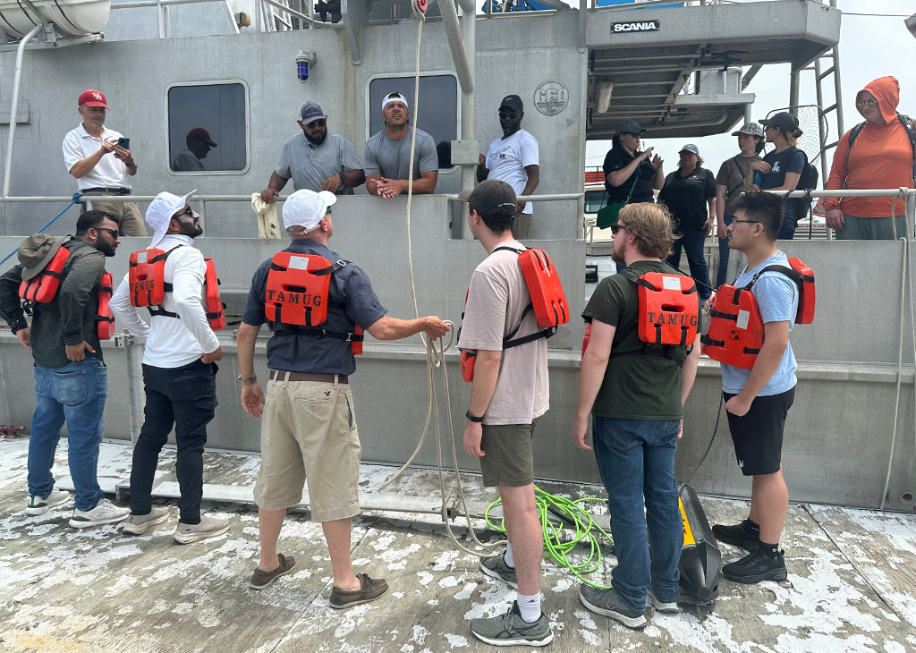 Students volunteers help assemble the side sonar onto the R/V Trident.