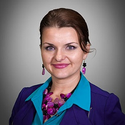 Portrait of a woman wearing a blue business jacket with her brown hair pulled back.